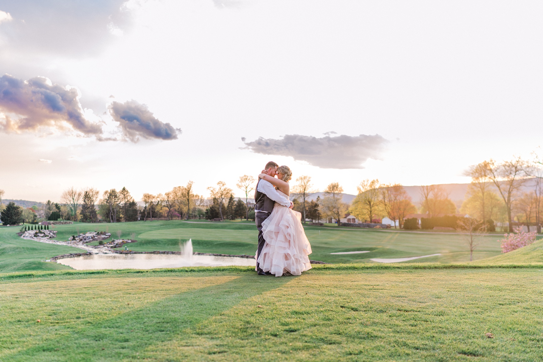 bride and groom kissing on golf course